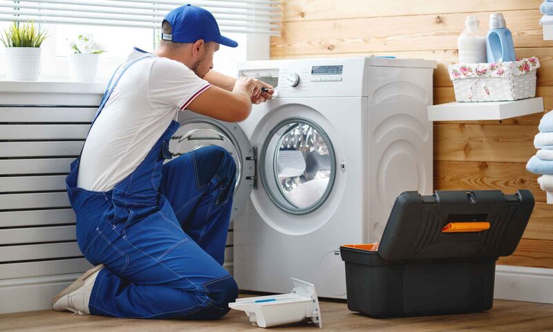 working man plumber repairs a washing machine in   laundry